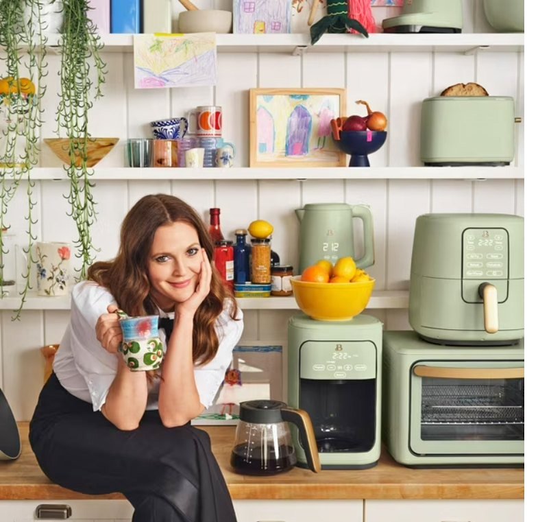 Women holding mug in kitchen with green appliances and shelves.