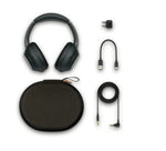 Black headphones with accessories including a carrying case, cable, and adapter