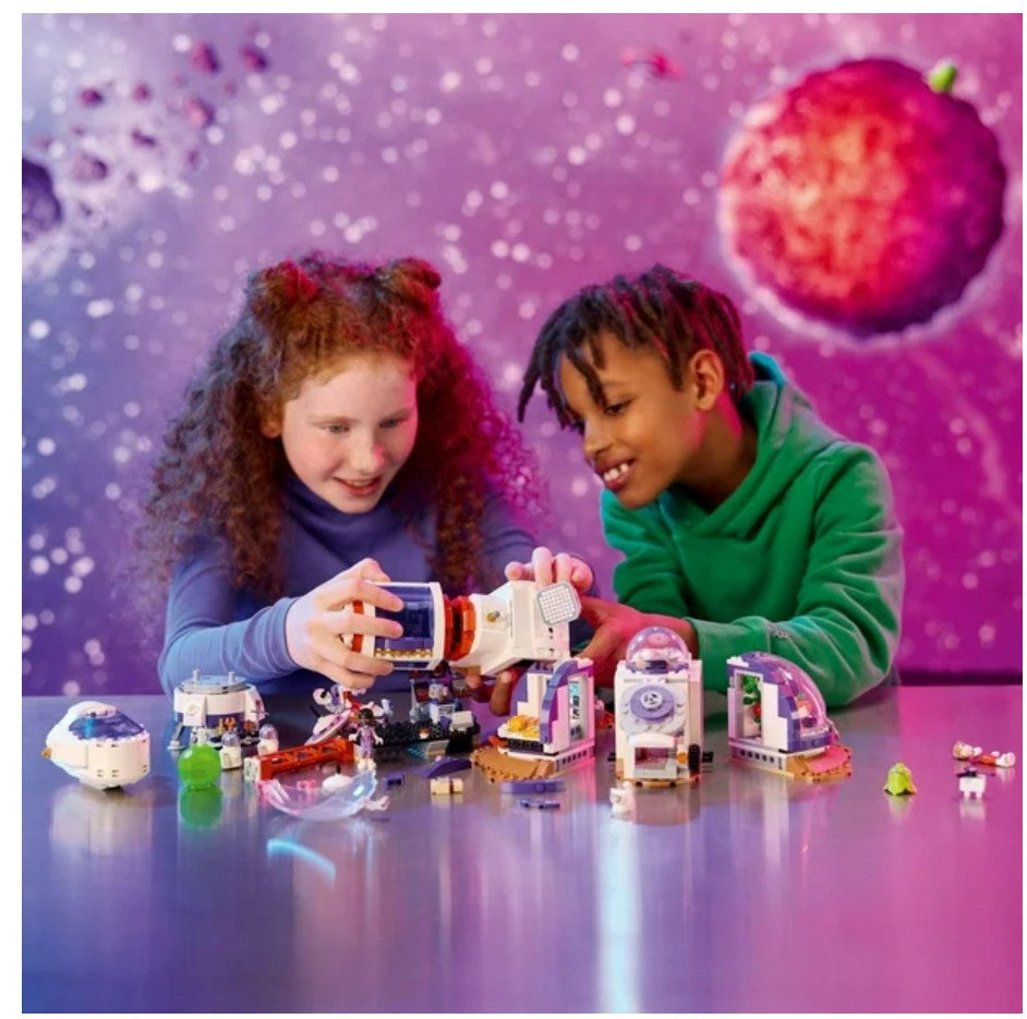 Two children playing with a toy set against a space-themed