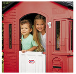 Two children peeking out from a red playhouse.