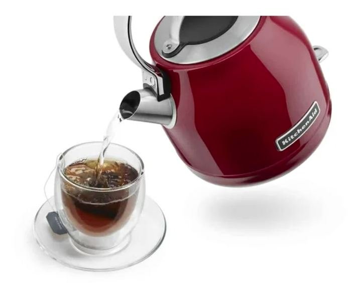 Red KitchenAid kettle pouring tea into a glass cup