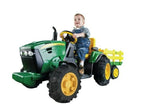 Child sitting on a toy tractor with a trailer
