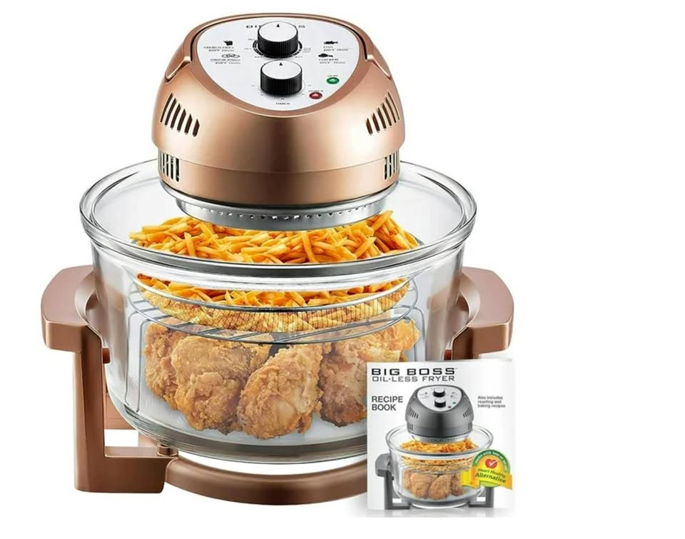 Hot air fryer with food items inside and a recipe book