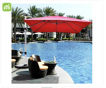 Red patio umbrella over a poolside area with chairs and palm trees
