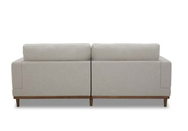 Beige sectional sofa with wooden legs.